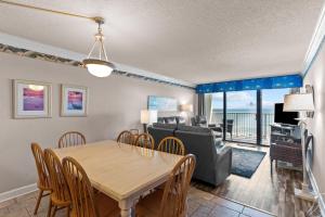 a dining room and living room with a table and chairs at Pelican Watch #405 in Carolina Beach