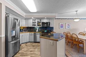 a kitchen with a stainless steel refrigerator and a table at Pelican Watch #405 in Carolina Beach