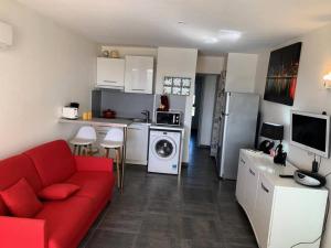 salon z czerwoną kanapą i kuchnią w obiekcie Résidence Port Nature Colline 4 - Appartement T2 4 pers. - Port Nature Colline 4 MAE-2774 w Cap d'Agde +1 zdjęcie