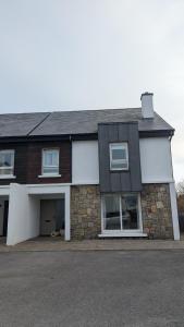 a white and brown house with a garage at Sruthan na Teorainn in Carraroe