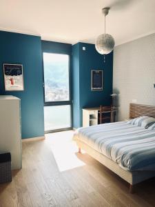 a bedroom with blue walls and a bed and a window at Le balcon du boulevard bellevue in Saint-Claude
