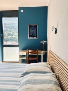 a bedroom with a bed and a blue wall at Le balcon du boulevard bellevue in Saint-Claude
