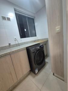 a washer and dryer in a bathroom with a sink at Apartamento moderno e funcional bem localizado in Balneário Camboriú