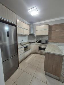a kitchen with wooden cabinets and a stainless steel refrigerator at Apartamento moderno e funcional bem localizado in Balneário Camboriú