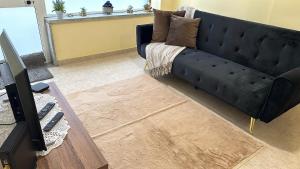 a living room with a black couch and a television at Casa Pessoa in Fátima