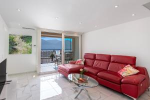 un soggiorno con divano rosso e tavolo in vetro di Red View Apartment - Happy Rentals a Ronco sopra Ascona
