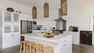 a white kitchen with a bowl of fruit on a counter at Stunning Ocean Views and Pool in Hardys Bay