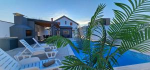 a house with a pool and chairs and a palm tree at Villa White Pearl Buna in Hodbina
