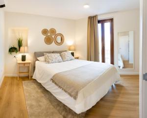 a white bedroom with a large bed and a window at Apartamentos Canterías in Cáceres