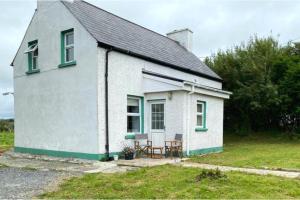 a small white house with a table and chairs outside at 3br-Sea View-Fireplace-Garden-Free Parking in Falcarragh