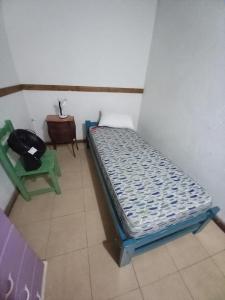 una pequeña habitación con una cama y una silla en Cabaña giardino, en Villa Giardino