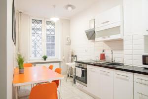 cocina con armarios blancos, mesa y sillas naranjas en Lily Apart - Private rooms in the Old Town, en Gdansk