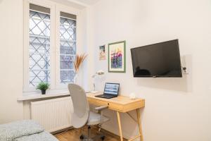 Un escritorio con una computadora portátil y un televisor en una pared. en Lily Apart - Private rooms in the Old Town, en Gdansk