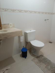 a bathroom with a white toilet and a blue trash can at Casa de campo Serra do Cipó in Serra do Cipo