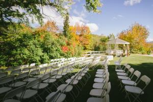 a row of white chairs in a field with a gazebo at Town & Country Inn & Resort in Gorham
