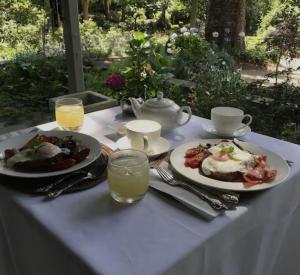 a white table with two plates of food and drinks at Foxglove Gardens in Tilba Tilba