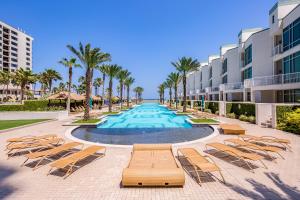 Una piscina tipo resort con tumbonas y palmeras. en Sapphire Bungalow #106, en South Padre Island