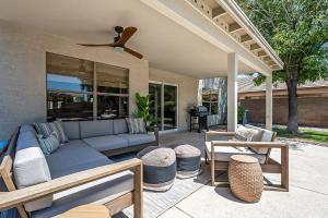 un patio con un sofá azul y algunas mesas en Dos Palmas Gilbert Poolside Retreat, en Gilbert