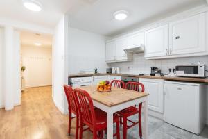 a kitchen with white cabinets and a wooden table with chairs at Spacious 3-Bed Apt in Dublin Center in Dublin