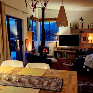 a living room with a table and a wood stove at Beachfront Sunset Bach in Piha
