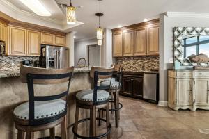 une cuisine avec des placards en bois et des tabourets de bar dans l'établissement The Oasis at Orange Beach 1707, à Orange Beach