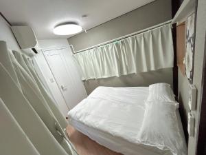 Un dormitorio pequeño con una cama blanca y una ventana. en 池袋巣鴨ハウス一棟丸ごと貸切りIkebukuro Sugamo House-Private Entire Building, en Tokio