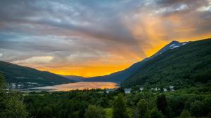 a rainbow in the sky over a lake with mountains at Villa Gratangen in Gratangen