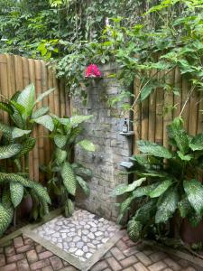 a fence with plants and a pink flower on a wall at Fox & The Firefly Cottages in Loboc