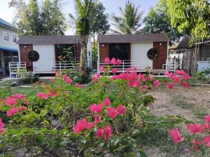 Ban Don Sawanบ้านวสุธันย์ฟูจิมินิมอล的房子前面有粉色花朵的花园