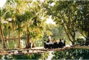 a group of people sitting at a table near a pond at El Questro - The Homestead in Kununurra +5 photos