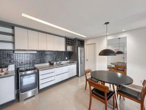 a kitchen with a table and a dining room at Loft Confortável e Elegante com Quarto Fechado in Campo Grande
