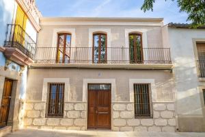 an old stone house with a balcony and a wooden door at Apartamentos Canterías in Cáceres
