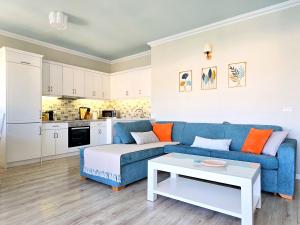 Eli's Seafront Apartment في سارنده: غرفة معيشة مع أريكة زرقاء وطاولة
