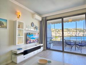 Eli's Seafront Apartment في سارنده: غرفة معيشة مع تلفزيون وطاولة مع كراسي