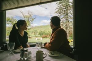 two women sitting at a table looking out a window at Town & Country Inn & Resort in Gorham