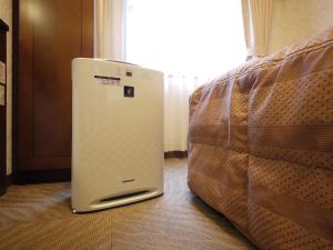 a small refrigerator sitting next to a bed at Hotel Route Inn Natori Iwanuma Inter Sendai Airport in Natori