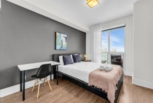 トロントにあるDowntown west Suitesのベッドと机と窓のある寝室
