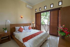 sypialnia z łóżkiem i dużym oknem w obiekcie Villa Chandra w mieście Seminyak