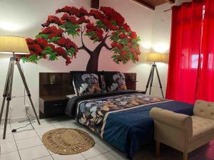 a bedroom with a bed with a tree on the wall at Poupeye in Sainte-Anne