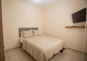 ein kleines Schlafzimmer mit einem Bett und einem Flachbildfernseher in der Unterkunft Departamento Nuevo en Hermosillo in Hermosillo
