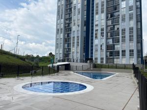 two pools in a courtyard in front of a tall building at Apartamento Turistico Monte Azul in Armenia