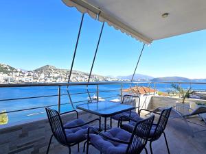 Eli's Seafront Apartment في سارنده: طاولة وكراسي على شرفة مطلة على الماء