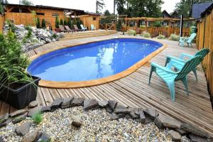 a pool on a wooden deck with a bench and a chair at BUBOVA Chata in Stará Lesná