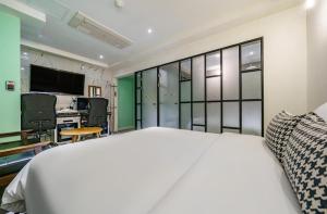 a bedroom with a large white bed and a television at Avenue Hotel in Osan