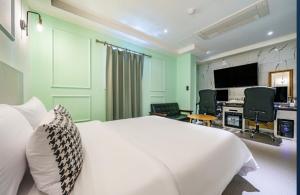 a bedroom with a white bed and a desk and a computer at Avenue Hotel in Osan +24 photos