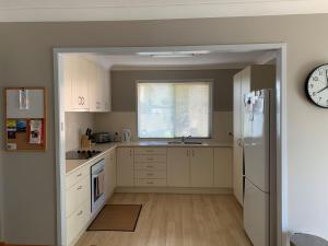 eine Küche mit weißen Schränken und einem weißen Kühlschrank in der Unterkunft Oxley's Rest in Harrington