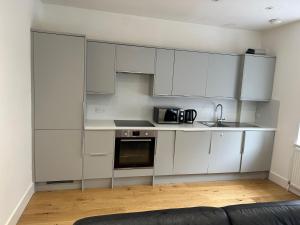 une cuisine avec des armoires blanches et un micro-ondes dans l'établissement En Suits room with your own bathroom and toilet, à Londres 18 autres photos