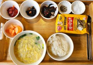 a wooden tray with bowls of soup and other food at 9 Brick Hotel in Seoul