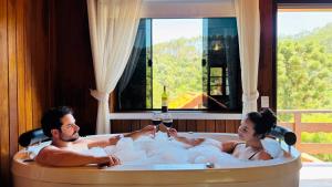 a man and woman in a bath tub with a glass of wine at Chalés Leopoldo em Monte Verde in Monte Verde