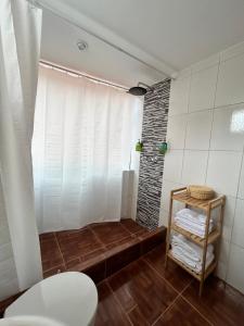 a bathroom with a shower with white curtains and a toilet at La Maison Samaï in Urubamba